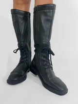 Botas de cuero negras de caña alta, con cordones y cierre lateral.