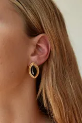 Aros tipo caravana de acero quirúrgico hipoalergénico color dorado con forma de ojo y piedra negra engarzada.