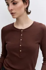 Remera de manga larga color negro, con cuello redondo y cierre frontal parcial con botones metálicos.