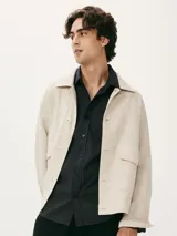 Camisa de manga larga con cierre frontal de botones, cuello clásico y bolsillo en el pecho. Presenta un diseño de rayas verticales finas en tonos azul y blanco.