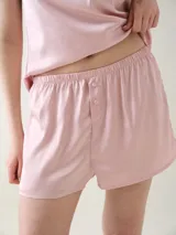 Short para dormir de satén rosado con cintura elastizada y botones decorativos en la parte frontal.