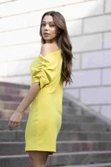 Vestido corto color lima, con escote asimétrico y manga corta.