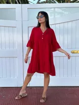 Vestido corto rojo de lino, con escote en V y dos botones de nácar, mangas acampanadas y ruedo con volado.