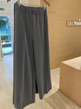 Pantalón gris de corte ancho con elástico en la cintura, botón decorativo y bolsillos laterales.