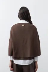 Saco tipo capa de punto color negro, con silueta fluida, corte amplio y cierre frontal con dos botones dorados.