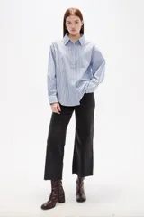 Camisa de algodón con diseño de rayas verticales en tonos azul y blanco, corte holgado, cuello camisero y cierre frontal con botones.