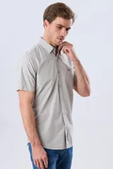 Camisa de manga corta de algodón en color celeste con microdiseño geométrico a cuadros, cuello camisero y bolsillo frontal con logo bordado.
