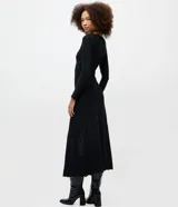 Vestido largo de malla texturizada con cuello redondo y manga larga. Presenta un corte evasé con acabado de encaje discreto, ofreciendo una caída fluida y elegante.