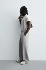 Pantalón jogger de corte relajado y pernera ancha, confeccionado en tejido de algodón con interior perchado. Cuenta con cintura elástica ajustable mediante cordón interior, bolsillos laterales y un bolsillo trasero de plastrón.