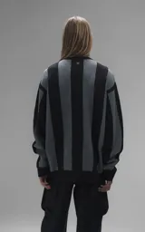 Sweater de punto con diseño a rayas verticales en negro y gris, cuello redondo y mangas largas. Presenta un estampado gráfico frontal con estilo deportivo retro que incluye el texto 'Ravers' y el número '90'. Cuenta con terminaciones en punto rib en cuello, puños y ruedo.