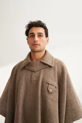 Poncho unisex de lana fina color marrón claro con cuello, cartera con broches a presión y bolsillo ojal. Diseño exclusivo de Don Baez, hecho 100% en Uruguay.
