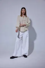 Camisa de manga larga con diseño de rayas verticales sutiles, cuello camisero con volados frontales y mangas abullonadas con puños ajustados.