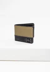 Billetera plegable bicolor, combinando tela tipo lona color verde oliva en la parte superior y material sintético negro en la inferior. Presenta un parche negro con el logo "XII INFINITE" en blanco y costuras decorativas en zigzag.