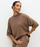 Blusa de punto color marrón, con cuello redondo alto y mangas cortas amplias con sisas desplazadas.