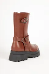 Bota biker negra de símil cuero, con punta redonda y apliques de tachas, hebilla y argolla. Plataforma tractor de 5cm y cierre lateral.