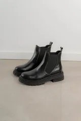 Bota Chelsea de cuero negro con elástico lateral y suela track.