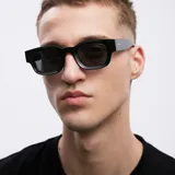 Lentes de sol negros con montura cuadrada gruesa y lentes polarizadas.