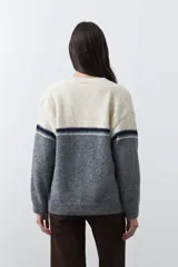 Cardigan de tejido jacquard en color azul marino y blanco, con diseño de conejitos en los laterales, cierre frontal con botones y cuello redondo.