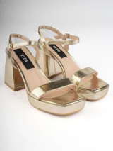 Sandalias doradas con plataforma, taco cuadrado y tira delgada ajustable al tobillo.