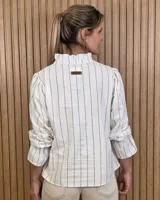 Blusa blanca de algodón con escote en V y cuello mao. Presenta mangas largas abullonadas con puños acampanados y fruncidos.
