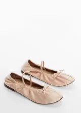 Zapato tipo bailarina color rosa pálido, de tejido satinado, con punta redonda, lazo decorativo y tira elástica sobre el empeine.