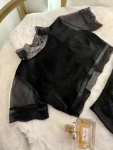 Conjunto de lencería compuesto por un top de cuello alto con mangas cortas y una bombacha de tiro alto. Ambas piezas combinan paneles de terciopelo, microtul transparente y detalles de encaje elastizado.