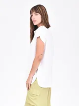 Camisa blanca de manga corta, con cuello camisero y botones frontales. Presenta un corte recto y holgado.