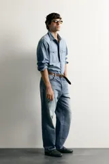 Pantalón jeans de corte relaxed fit, color azul con efecto ligeramente lavado, perneras rectas con raya de planchado frontal y diseño de cinco bolsillos.