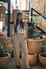 Pantalón de corte recto y tiro alto, confeccionado en lino color blanco. Presenta cierre frontal con botón y bolsillos laterales.