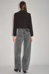 Jean de corte wide leg en color gris oscuro con efecto lavado. Presenta costuras verticales decorativas a lo largo de las piernas y cierre frontal con botón y cremallera.