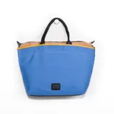 Cartera tipo tote azul con detalles en beige y negro, con doble asa de mano y cierre superior.
