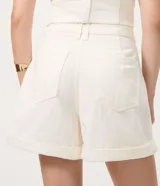 Short de sarga color blanco, de corte evasé con diseño de tiro medio, pasacintos en la cintura, bolsillos y botamangas con vuelta.