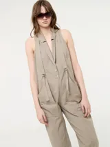 Mono color beige con bolsillos delanteros y tirantes ajustables.