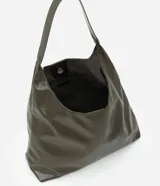 Cartera hobo grande de poliuretano color verde militar, con diseño slouchy, base estructurada y una única asa larga para llevar al hombro. Cuenta con cierre de botón a presión y amplio compartimento interior.