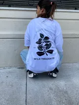 Remera blanca de algodón con estampa en la espalda que incluye texto y diseño de hojas.