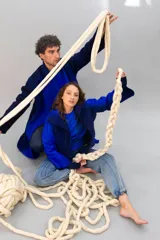 Chaqueta azul con mangas largas, cuello alto y cierre frontal con cordón. Diseño calado en el frente y mangas con patrón de rombos. Confeccionada en lana merino.