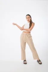 Pantalón de tela color beige, con cintura alta elastizada y cordón ajustable.