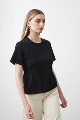 Remera de manga corta y cuello redondo, confeccionada en algodón. Presenta costuras verticales visibles en el frente que aportan estructura y un efecto entallado en la cintura.