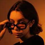 Lentes de sol unisex negros con armazón 3D redondeado y lentes polarizados color naranja con protección UV400.