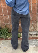 Jean de corte recto y tiro medio color gris con efecto acid wash. Presenta bolsillos traseros con bordado de brújula y parche de cuero sintético con logo en la parte posterior de la cintura.