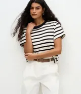Remera de corte boxy confeccionada en algodón, con diseño de rayas horizontales en blanco y negro, cuello redondo en color negro contrastante y mangas cortas.