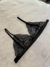 Conjunto de lencería de tres piezas en encaje negro. Incluye bralette con breteles regulables, collarín integrado con cuello ajustable y tanga regulable con corte media less.