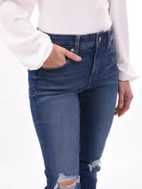 Pantalón de jean skinny azul con roturas en las rodillas y ruedo desflecado.