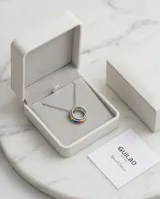 Collar de acero con dije compuesto por tres aros entrelazados, uno de ellos con detalle de esmalte multicolor. Cadena de eslabones finos.
