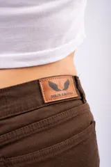 Pantalón de corte wide leg en color marrón, confeccionado en tejido con elastano. Presenta tiro medio, cierre frontal con botón y bolsillos laterales.