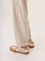 Pantalon de corte recto y tiro medio, confeccionado en tejido de lana con sutiles rayas verticales. Presenta bolsillos traseros aplicados, costuras reforzadas en las rodillas y ruedo con dobladillo.