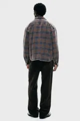 Camisa de franela de algodón suave con efecto lavado, corte relajado. Presenta cuello inglés, tapeta clásica de botones, un bolsillo superior abierto en el pecho y canesú en la espalda. Las mangas son largas con tapeta y puños abotonados, y el bajo es ligeramente redondeado. El estampado es a cuadros en tonos grises y naranjas.