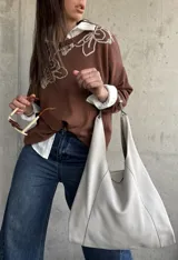 Sweater de punto color chocolate, de corte holgado, manga larga y cuello redondo con delicados bordados contrastantes en el frente.