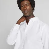 Camisa blanca de corte recto, con cuello abotonado y mangas largas.