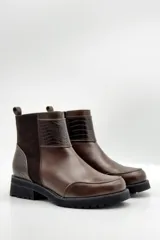 Botas de cuero color marrón con detalles de textura de cocodrilo en los laterales y la parte superior. Tienen cierre lateral y suela robusta negra.